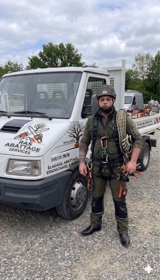 Élagueur grimpeur de RAS Élagage en tenue de sécurité devant le camion de l'entreprise
